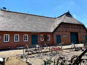 Hoisdorf: Teilansicht Gebäude Stormarnsches Dorfmuseum, davor landwirtschaftliche Geräte
