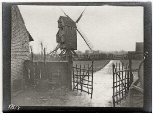 Nicht identifizierbare Ortschaft (Belgien/Nordfrankreich): Windmühle, im im Vordergrund Gatter und landwirtschaftliches Feld