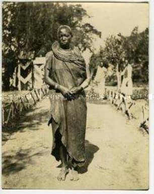 Proträt einer auf einem Weg stehenden Massai-Frau