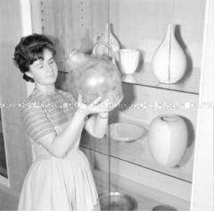 Besucherin der Ausstellung zum Kunsthandwerk in der DDR betrachtet eine Vase
