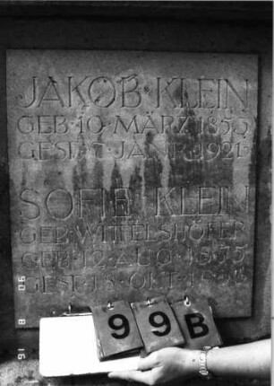 Grabstein 99 (Index: 99618523) Maße HxBxT: 183x140x30 cm Beschreibung: aufgesetzte Urne Symbolik: Verzierungen Besonderheit: Doppelgrab für Eheleute (mit Tochter?): Grabstein 99B