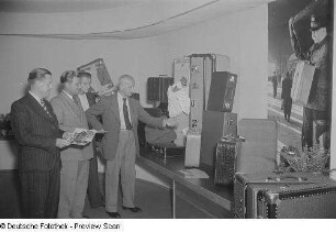 Besucher vor Messestand mit Koffern