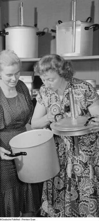 Zwei Frauen begutachten einen Einkochtopf mit Thermometer auf der Leipziger Herbstmesse 1954