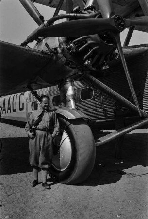 Verkehrsflugzeug : Portrait eines nicht näher benannten Mannes, der unter einem Flügel einer englischen Verkehrsmaschine Aufstellung bezogen hat.