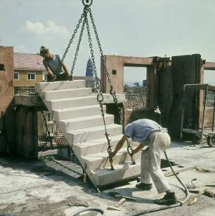 Dresden. Absetzen eines Treppenfertigteils, an Anschlagseilen und -ketten hängend, am Montageort eines Wohnhauses