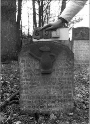 Grabstein 591 (Index: 100115296) Material: Sandstein Zustand: verwittert Maße HxBxT: 78x53x11 cm Beschreibung: Stele mit Rundbogenabschluß Symbolik: Levitenkanne: Grabstein 591