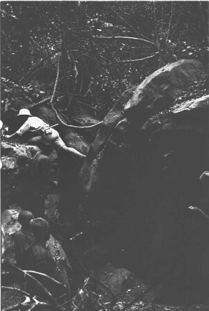 Alfred Mayer-Gürr vor der Höhle von Namjani : Alfred Mayer-Gürr springt vor dem Eingang zur unteren Höhle von Namjani über einen Felsspalt.