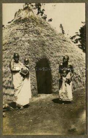 Zwei Wadschagga-Frauen mit Kleinkindern vor einer Hütte