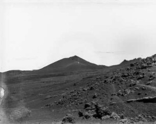 Vulkanlandschaft : Blick über ein unebenes Feld auf einen Vulkan.