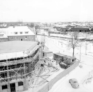 Erweiterungsbau [später Gebäude C] mit Kreistagssitzungssaal: IV. Bauabschnitt: Kreistagssitzungssaal mit Bedachung und Gerüst: dahinter Wohnblock an Reimer-Hansen-Straße: rechts Bauzaun und Baubuden: dahinter Bahngleise und Güterschuppen: Winter