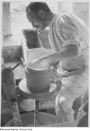 Töpfer beim Drehen eines Tongefäßes an der Drehscheibe, Töpferei Paul Mirisch, Pulsnitz : Pulsnitz. Töpferei Paul Mirisch. Formen eines Tongefäßes an der Drehscheibe. Arbeit mit der Hand