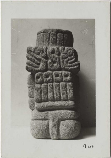 View of a squatting, richly decorated figure of the wind god Quetzalcoatl in connection with emblems of the rain god Tlaloc. Material: tezontli. Height 39 cm (B.T.) (back view)