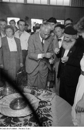Zwei Personen beim Entzünden von Räucherstäbchen, umringt von Publikum auf der Leipziger Herbstmesse 1954