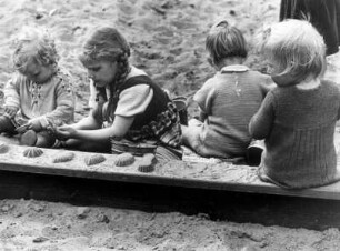 Kinder spielen in einem Sandkasten mit Sandformen