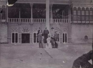 Gruppenportrait : Portraitaufnahme von einer Frau mit Kind und fünf Männern in einem Innenhof in Bagdad. Rechts vorne der Geograph Hugo Grothe (1869-1954).
