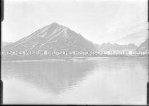 Dunkler Berg mit Schneefurchen, Spiegelung im Fjord, Nordlandreise, Norwegen