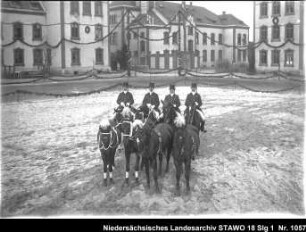Dressur- und Reitschule in der Artilleriekaserne Wolfenbüttel, Lindener Straße Enthält: Vier Reiter im Reitdress mit Zylinder halten vier Pferde am langen Zügel