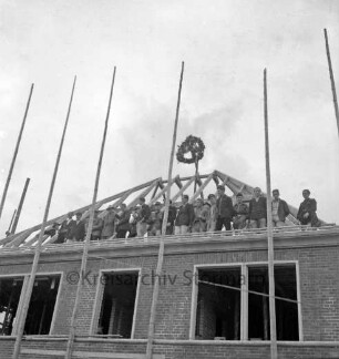 Verwaltungsgebäude: Lübecker Straße: in Bau: Richtfest: Rohbau mit Gerüst, Teilansicht: auf Dachstuhl Richtkrone, Handwerker, 1. September 1953