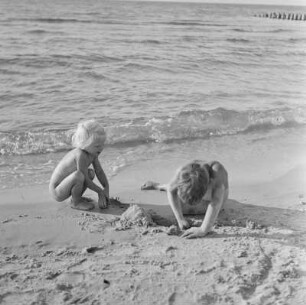 Zwei nackte Kinder spielen am Stand