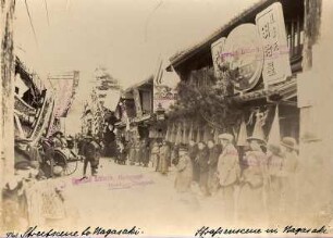 Nagasaki, Japan. Blick in eine belebte Geschäftsstraße mit Einheimischen und Touristen in Rikschas