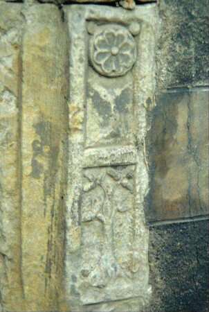 Reliefstein im Mauerwerk der Kirche mit Blume und Lebensbaum