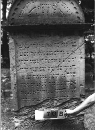 Grabstein 70 (Index: 100110822) Material: Sandstein Zustand: oberhalb Sockels Abschieferungen mit großem Textverlust, Giebel beschädigt, ehemals blau ausgemalte Schrift Maße HxBxT: 202x100x26 cm Beschreibung: Stele, Sockel profiliert, Rundbogenabschluß mit Rundbogenfries und Verdachung, Schriftfelder eingetieft Besonderheit: kulturhistorisch wertvoll / künstl.-formale und hist.-wiss. Gründe (Inschrift, Gemeindestellung): Grabstein 70B