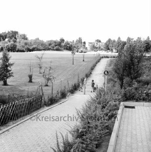 Stadion am Wendum: vorne Fußweg, links eine Rasenfläche, mittig der Sportplatz, dahinter die Baustelle für den Umkleidetrakt, dahinter Gebäude der Feldstraße: Blick nach Nordosten