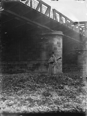 Soldat vor Brücke : Ein Soldat mit einem Gewehr vor einer Stahlfachwerkbrücke.