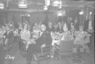 Abendgesellschaft im geschmückten Festsaal des Hochseepassagierdampfers "Bremen", an Tischen sitzend