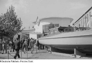 Messebesucher vor dem Ausstellungsgebäude der IFA (Industrieverband Fahrzeugbau), im Vordergrund ein Motorboot