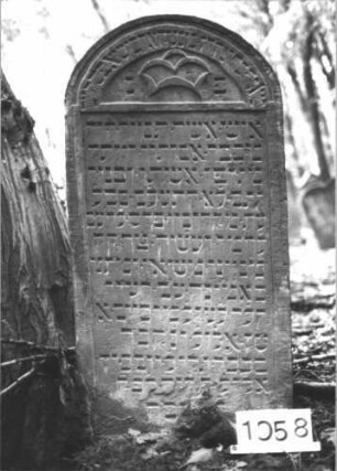 Grabstein 1058 (Index: 99899682) Material: Sandstein Zustand: unten verwittert, sonst gut erhalten Maße HxBxT: 124x62x10 cm Beschreibung: Stele mit Rundbogenabschluss, im Bogenfeld stilisierte Krone Symbolik: Krone: Grabstein 1058