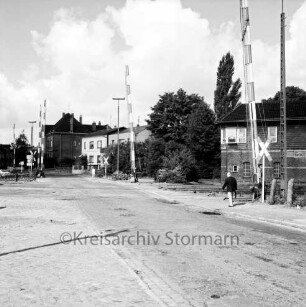 Bahnübergang Ratzeburger Straße: Blick von Osten: Zwillingsschranken: beide Schrankenpaare geöffnet: Mann auf Fußgängerweg: rechts Stellwerk: Andreaskreuze, Verkehrsschilder, Straßenlampen: hinten Häuser