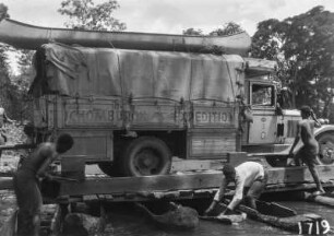 Lkw auf einem Floß : Männer sichern einen Lkw der Schomburgk-Expedition auf einem Floß