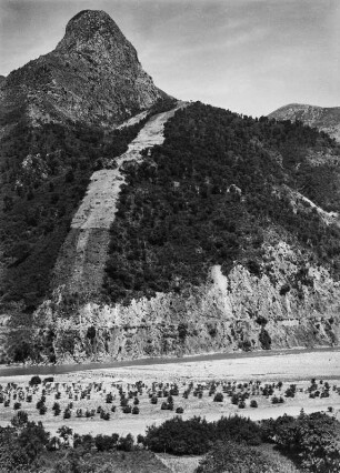 Berglandschaft : Blick auf den Oued Agrioun nördlich Oulad bou Zil. Im Flusstal befinden sich vereinzelte Lorbeerbüsche. Am Berghang ist eine Schneise mit Weizenfeldern zwischen Macchiebewachsung und Eichen zu erkennen.