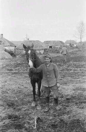 Zweiter Weltkrieg. Zur Einquartierung. Sowjetunion. Angehöriger der deutschen Wehrmacht mit Reitpferd