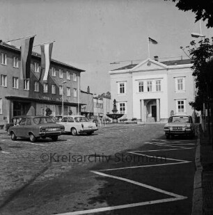 Marktplatz: links und rechts parkende Pkws: links Hauptstelle der Kreissparkasse Stormarn: rechts hinten Rathaus: in der Mitte Gänselieselbrunnen