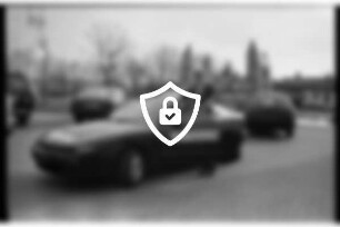Autohaus Homburg: Hammoorer Weg: Parkplatz: Juniorchef [Name maskiert] an offener Autotür von Testwagen Toyota Celica: hinten Autos, Hüpfburg, Werbefahnen, Straße: 26. März 1990