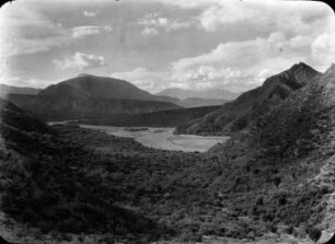 Tal des Rio Grande : In der Bildmitte der Flusslauf. Viel Vegetation an den Ufern und auf der Mizque-Niederung. Im Hintergrund Blick auf den Cerro Quinore.
