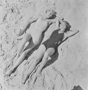 Zwei Frauen in Bademode liegen am Strand