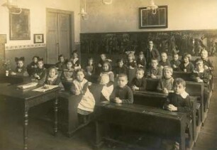 Gruppenaufnahme einer gemischten Schulklasse, im Klassenzimmer sitzend