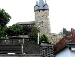 Evangelische Kirche - Kirchturm (frühgotisch 13 Jhd) von Norden mit Schießscharten in den Mittelgeschossen (Obergeschoß ehemals mit Wehrplattform) über Kirchhofmauer