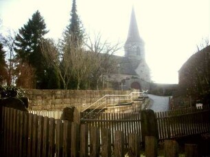 Ansicht von Nordosten aus dem Ort mit Kirche (Neubau 15 Jh auf Romanischem Vorgänger) im Kirchhof in erhöhter Lage am Ortsrand