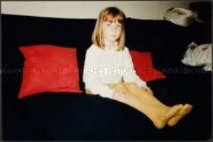 Kleines Mädchen mit gelber Strumpfhose auf einem dunklen Sofa sitzend (Sonderthema: Ein Bild von mir - Selbstporträts und Selbstdarstellungen)