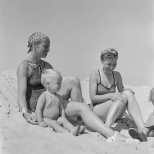 Elisabeth Gremmler (Erste von rechts) sitzt neben einer weiteren Frau und einem Kleinkind am Strand