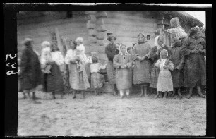 Einheimische Frauen und Kinder vor einem Holzhaus