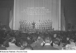 Blick vom Zuschauerraum auf einen Chor sowie Chorleiter auf einer Bühne bei einer Kulturveranstaltung in Halle II