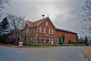 Papendorf: Langeloher Weg 1: ehemalige Gastwirtschaft Hugo Schmidt: giebelständiges Backsteingebäude: Traufseite mit Lisenen, Zwerchgiebel, Giebelzier aus Holz: Straßenfront mit Eingangstür, Wirtshausschild, Giebelzier, Wetterfahne, auf Dach Sirene: rechts Querbau Wirtschaftstrakt