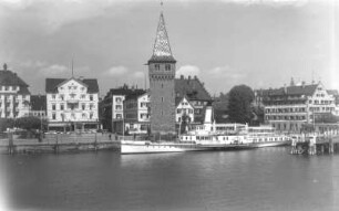 Lindau (Bodensee). Seehafen mit vor Anker liegendem Personen-Seitenraddampfer "München". Blick von der Löwenmole zum Hafenplatz mit Altem Leuchtturm (Mangturm; 12. Jh., Helm 19. Jh.)