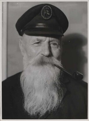 Portrait eines älteren Mannes, der eine Schiffermütze mit der Aufschrift "MV Insel Föhr" trägt