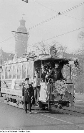 Musizierende Karnevalisten und Personal auf einer geschmückten Straßenbahn
